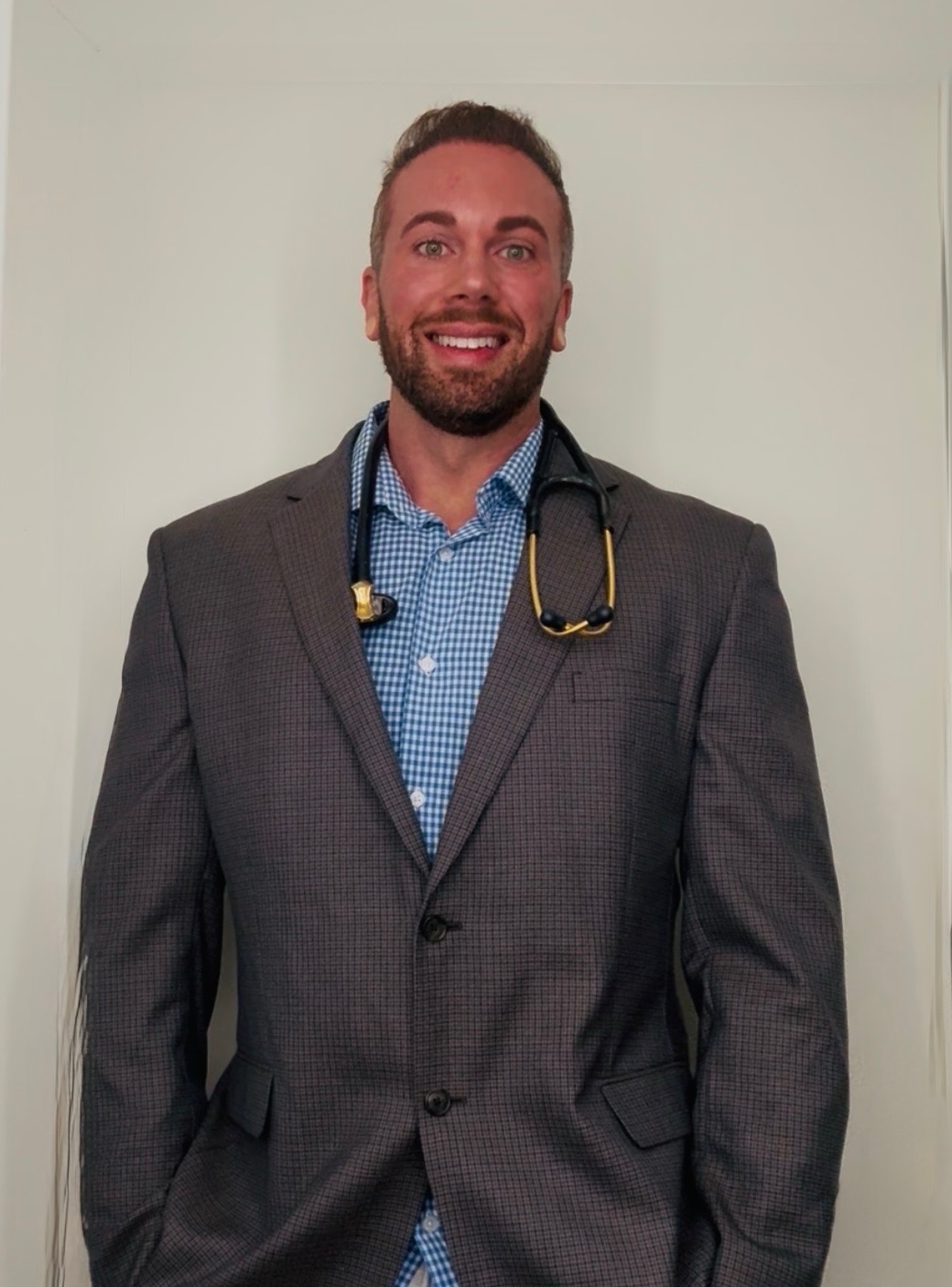 Daniel Lackey wearing a suit and stethoscope